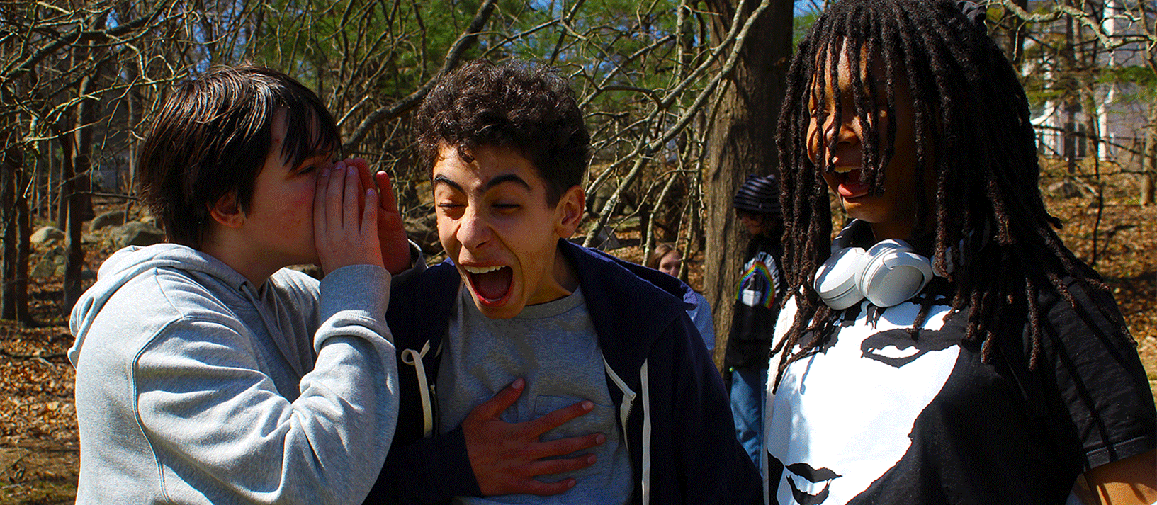 three students outside on playground laughing